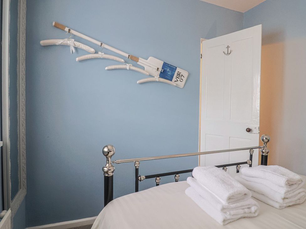 A bedroom with a bed, towels, and an oar mounted on the wall at Riverdance Cottage in Lyme Regis