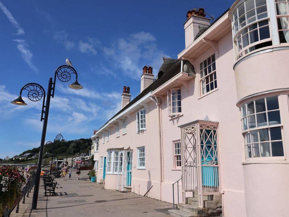 A building with benches and flowers along a walkway at Riverdance Cottage in Lyme Regis