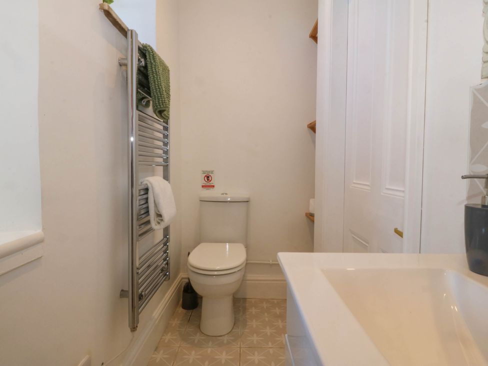 A bathroom with a toilet a towel rack with towels and a sink at Ael Y Fron in Aberdaron