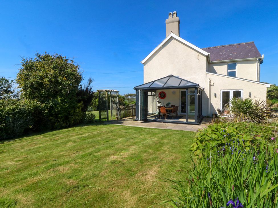 A house with a glass conservatory and a green lawn garden at Ael Y Fron in Aberdaron