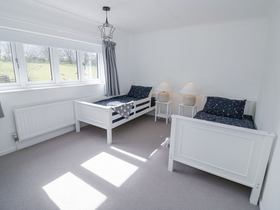 A bedroom with two single beds with star patterned bedding and two bedside tables with lamps at New House Farm in Wappenbury near Leamington Spa