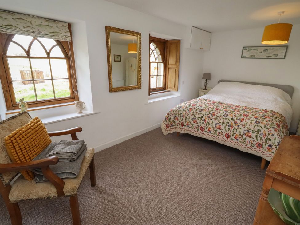 A bedroom with a bed and windows at The Coach House in Crookham near Cornhill-On-Tweed