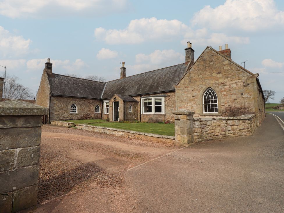 A stone house with a garden and pathway at The Coach House in Crookham near Cornhill-On-Tweed
