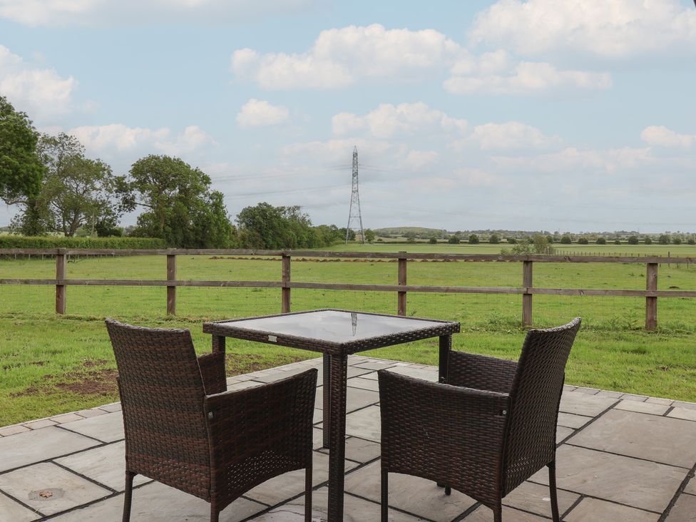 A patio with a table and chairs overlooking a field at Lodge 1 in Strensall