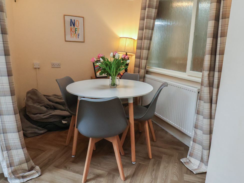A dining room with a table and chairs and a vase of flowers at Bridlington Bay House in Bridlington