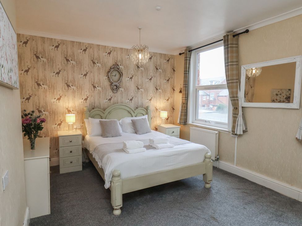 A bedroom with a bed, nightstand, and window at Bridlington Bay House in Bridlington