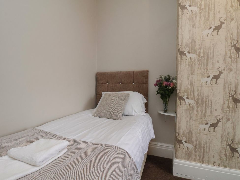 A bedroom with a bed, pillows, and a flower vase at Bridlington Bay House in Bridlington
