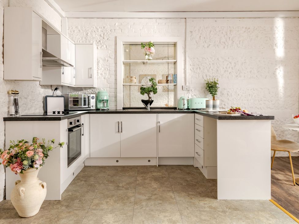 A kitchen with a countertop, oven, and shelves at Primrose in Blandford Forum