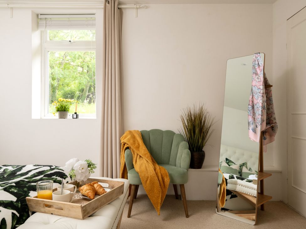 A bedroom with an armchair and a tray of breakfast at Primrose in Blandford Forum