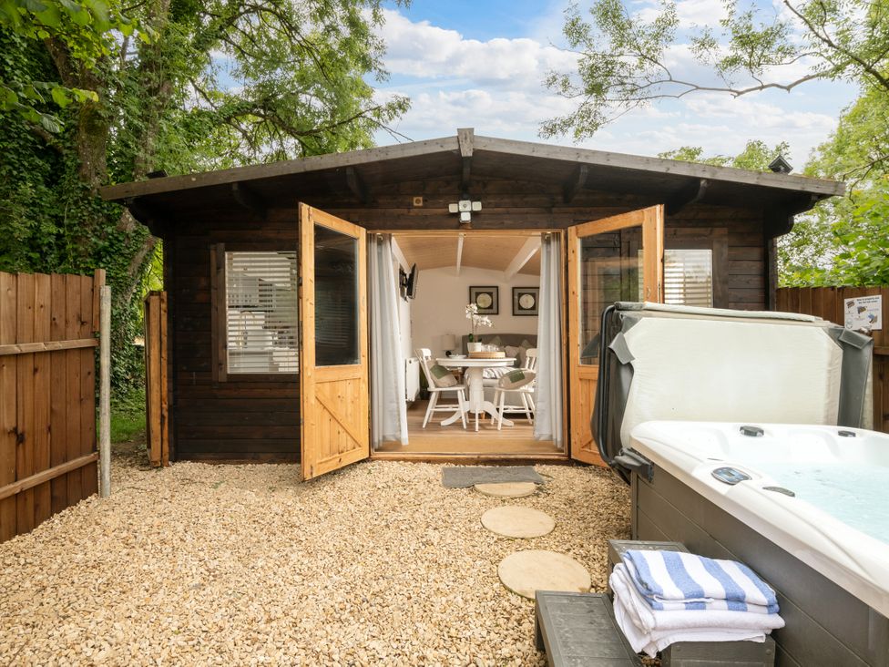 An outdoor view of a garden with a hot tub and a cabin at Hazel in Blandford Forum
