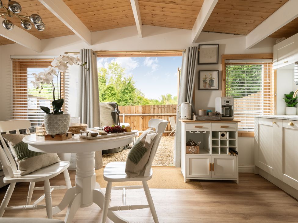 A dining area with a table, chairs, and a sliding door to the garden at Hazel in Blandford Forum