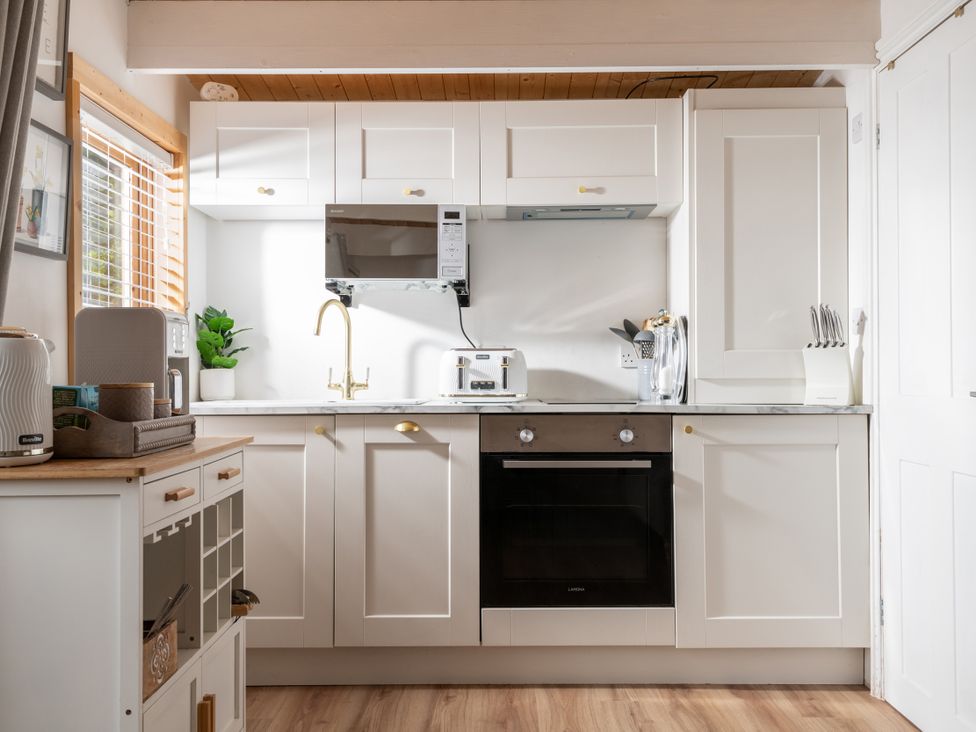 A kitchen with cabinets, sink, toaster, and oven at Hazel in Blandford Forum