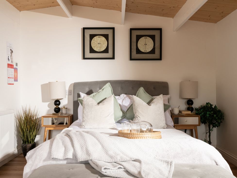 A bedroom with a bed, nightstands, lamps and wall art at Hazel in Blandford Forum