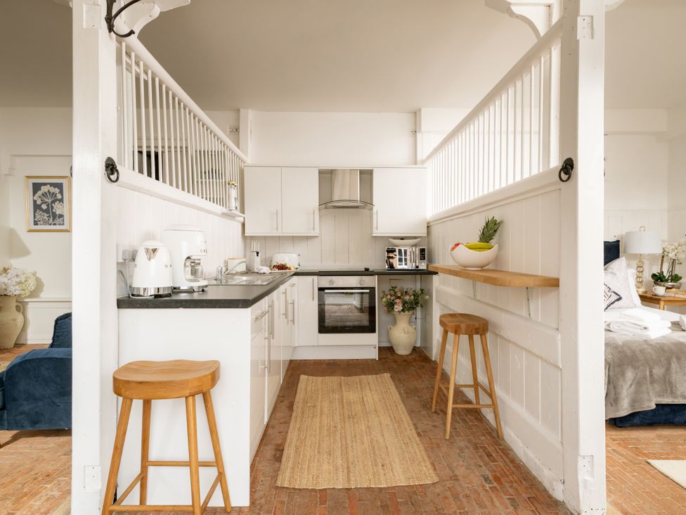 A kitchen with stools and an oven at Stable in Blandford Forum