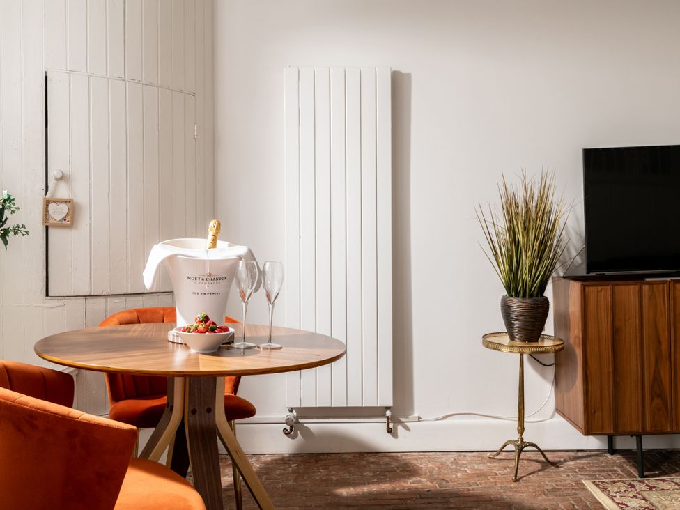 A living room with a table and champagne bucket at Stable in Blandford Forum