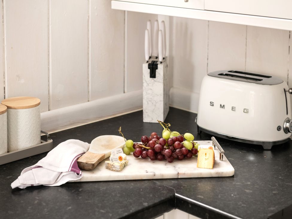 A kitchen with grapes and cheese on a cutting board at Stable in Blandford Forum