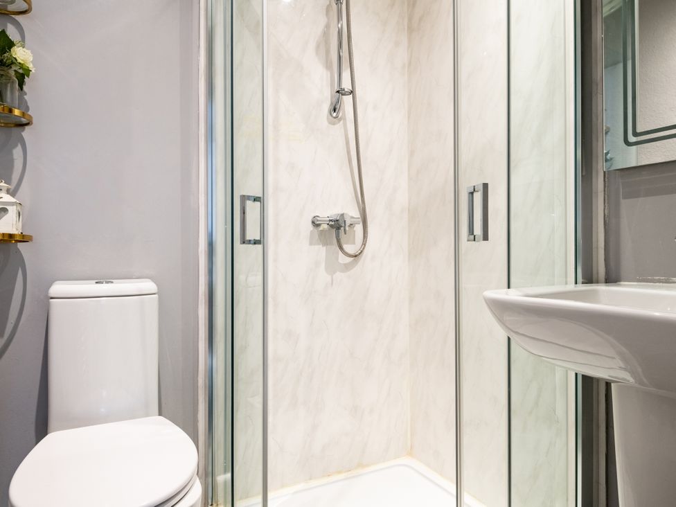 A bathroom with a shower, toilet, and sink at Stable in Blandford Forum