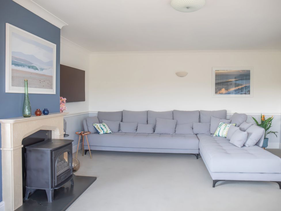 A living room with a gray sofa and fireplace at Newquay Tamarisk Lodge on the Gannel in Newquay