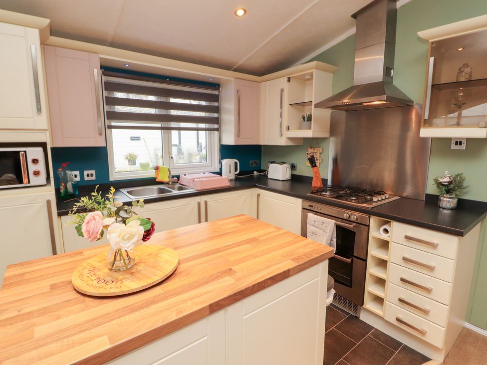 A kitchen with a stove and microwave at Rosie's Zen Den High Hesket near Armathwaite
