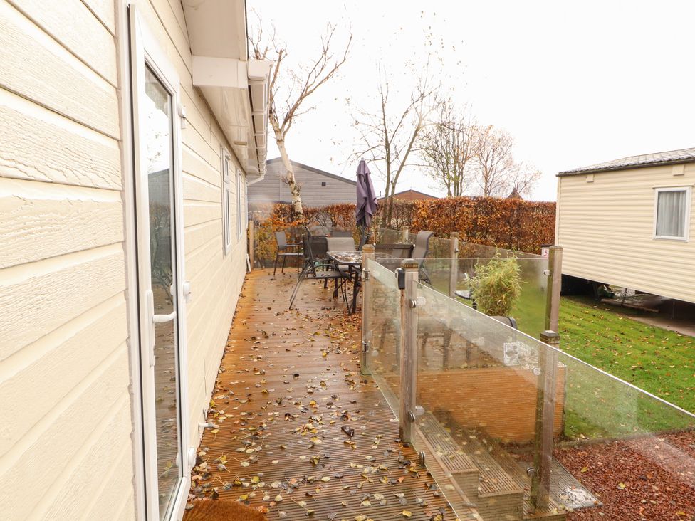 An outdoor deck with chairs and a table at Rosie's Zen Den in High Hesket near Armathwaite