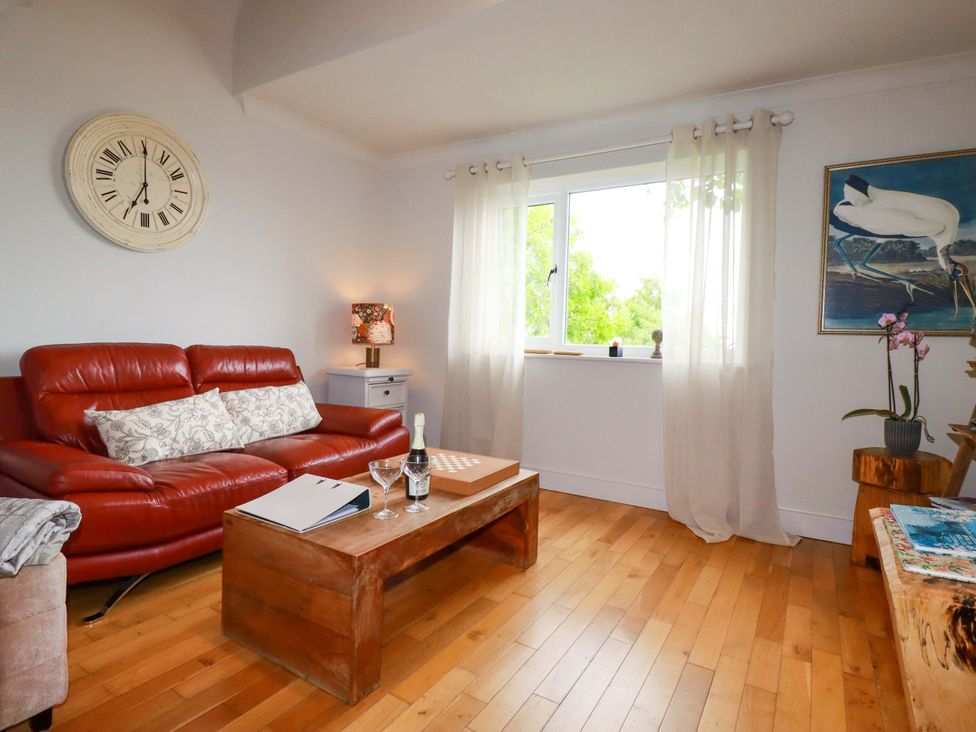 A living room with a sofa, coffee table and window at Sea View in St Austell