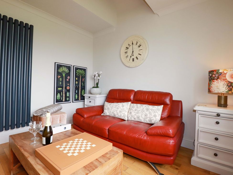 A living room with a red sofa and coffee table at Sea View in St Austell