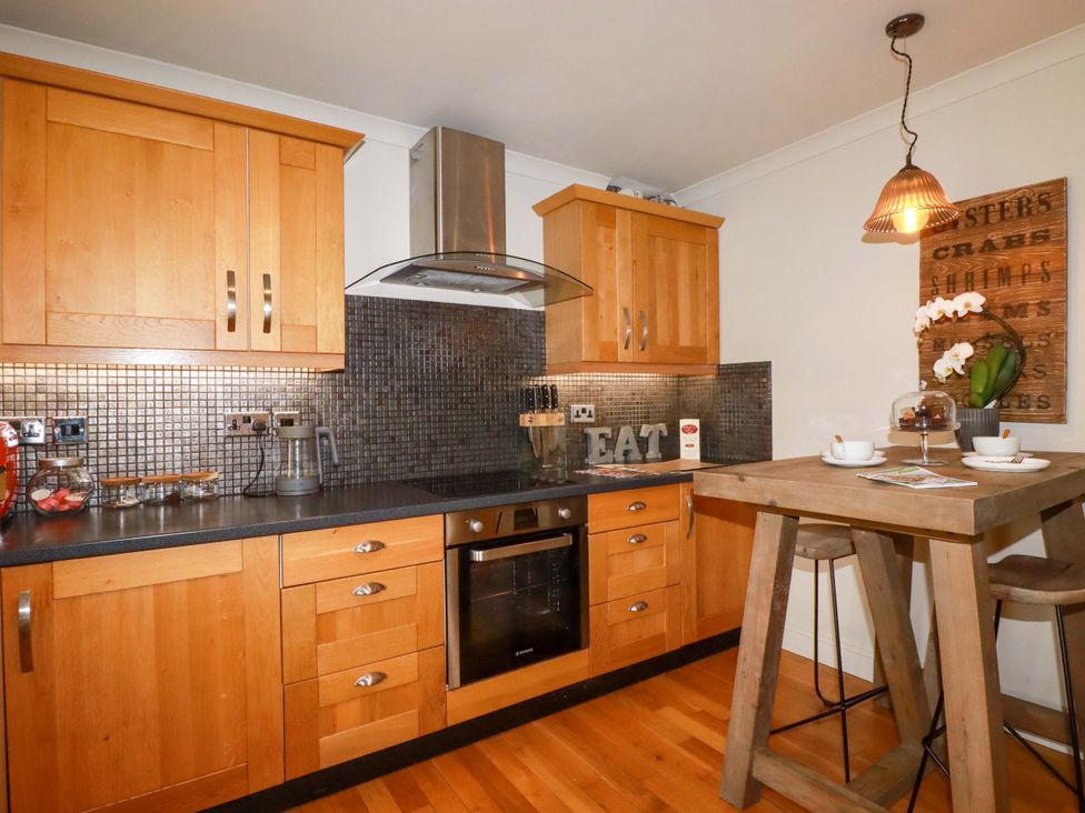 A kitchen with wooden cabinets and a table at Sea View in St Austell