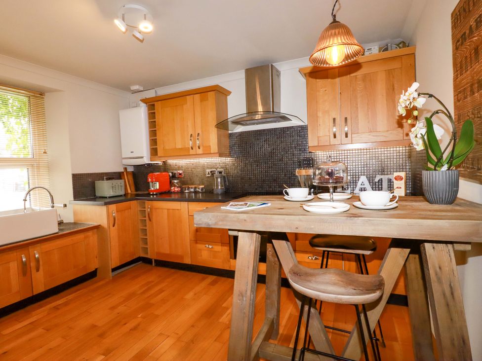 A kitchen with wooden cabinets and a table at Sea View in St Austell