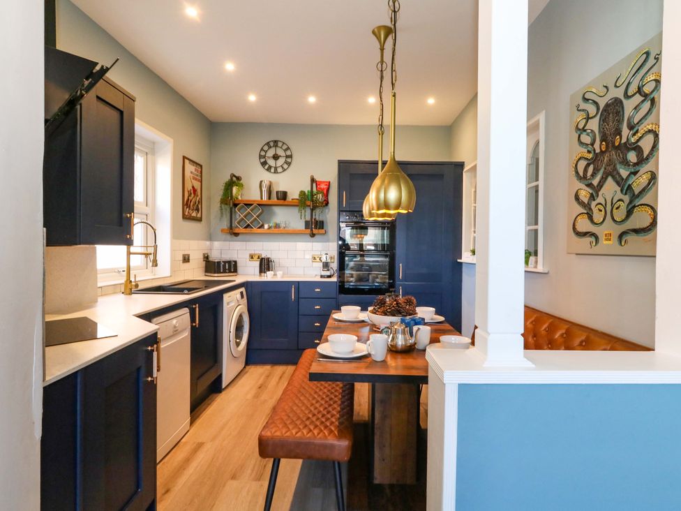 A kitchen with cabinets, a table, and appliances at The Old Post Office in Weymouth