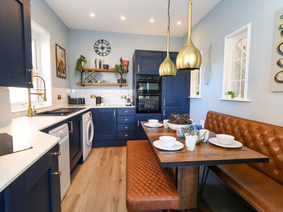 A kitchen with blue cabinets and wooden table at The Old Post Office in Weymouth