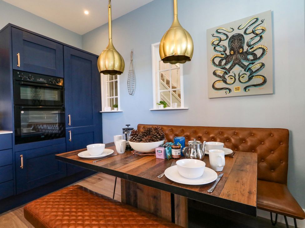 A kitchen with a dining set and decorative art at The Old Post Office in Weymouth