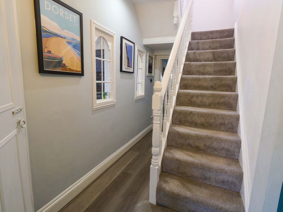 A hallway with a staircase and framed pictures at The Old Post Office in Weymouth