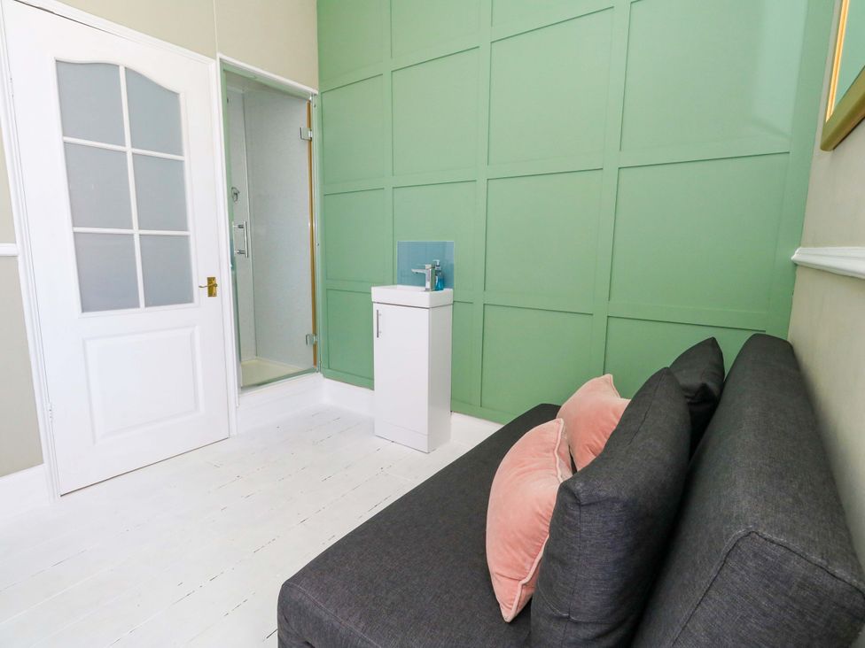 A bathroom with a shower, sink, and sofa at The Old Post Office in Weymouth