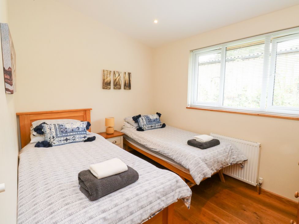 A bedroom with two beds and a window at Gloccamaura in Bovey Tracey