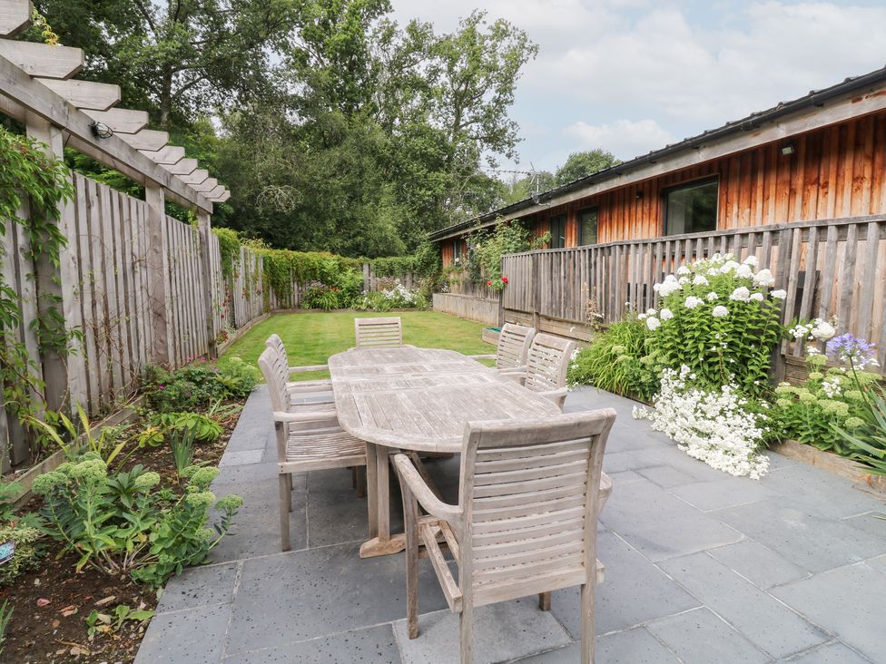A garden with a wooden table and chairs at Gloccamaura in Bovey Tracey