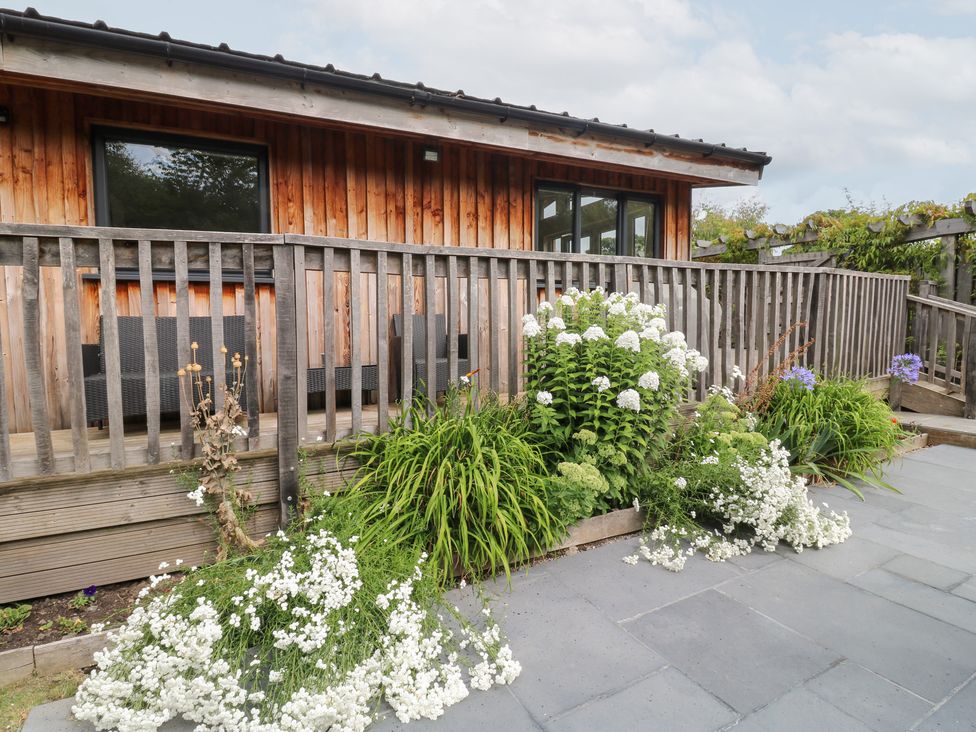 An outdoor area with a wooden deck and flowers at Gloccamaura in Bovey Tracey