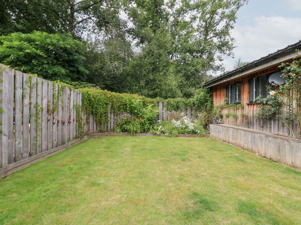 A garden with grass and a flower bed at Gloccamaura in Bovey Tracey