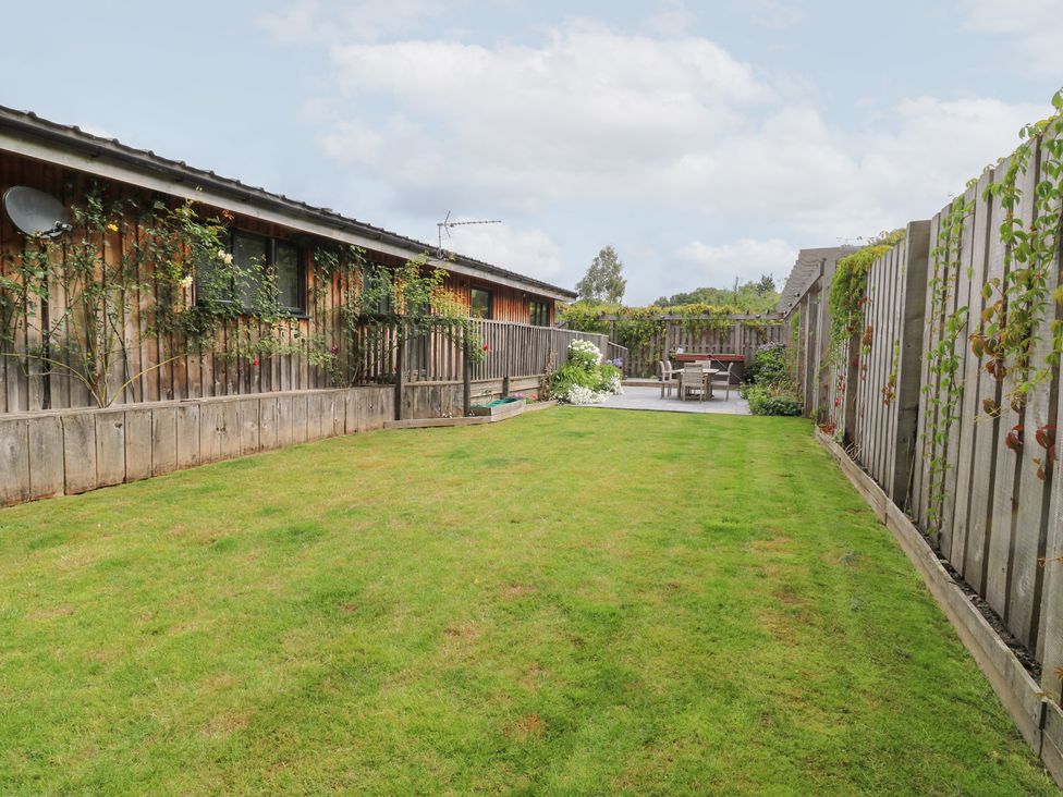 A garden with grass and seating area at Gloccamaura in Bovey Tracey