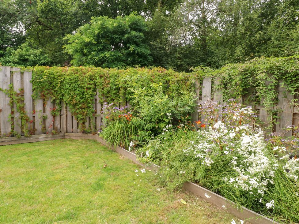 A garden with grass and flower beds at Gloccamaura in Bovey Tracey