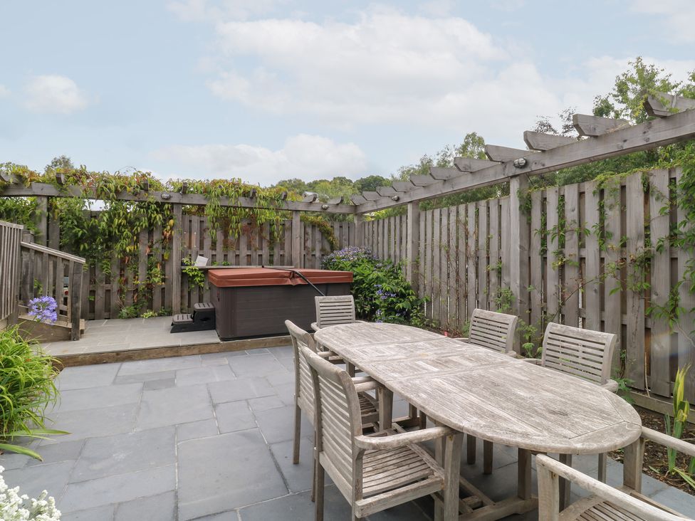 A garden with a dining table and hot tub at Gloccamaura in Bovey Tracey