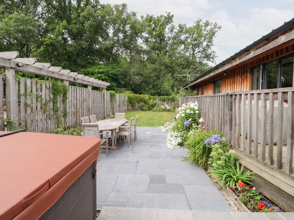 A garden with a hot tub and a table with chairs at Gloccamaura in Bovey Tracey