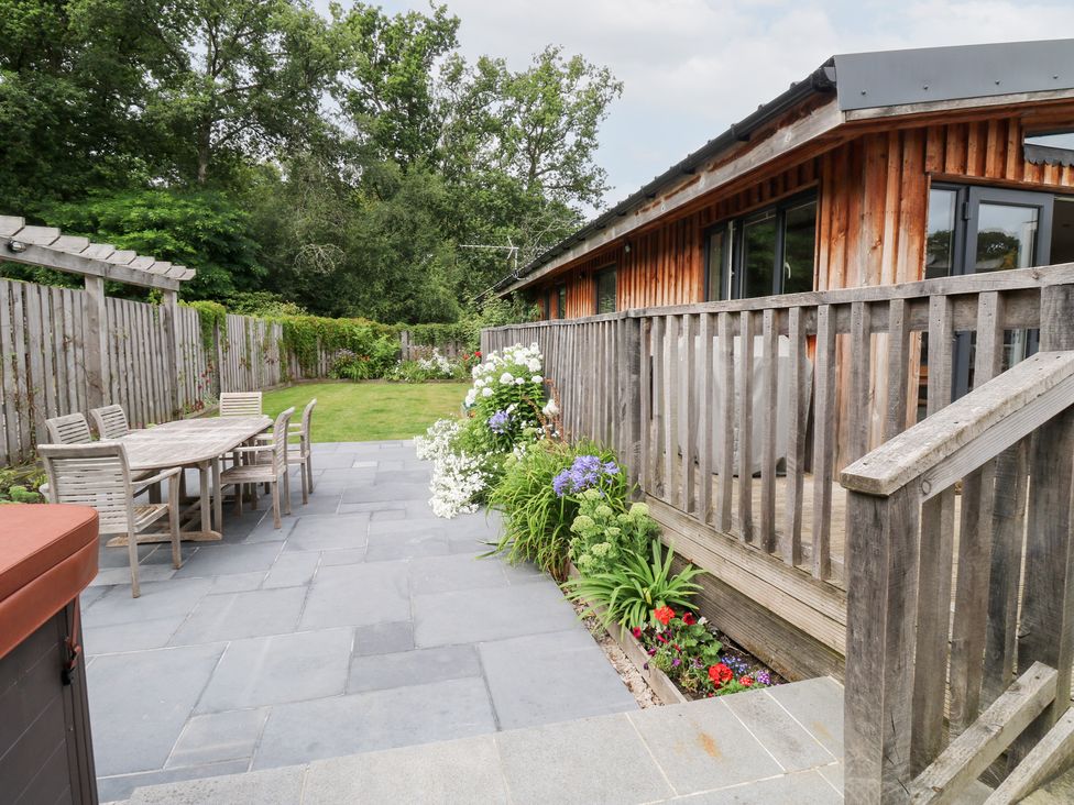 An outdoor patio area with a wooden table and chairs at Gloccamaura in Bovey Tracey