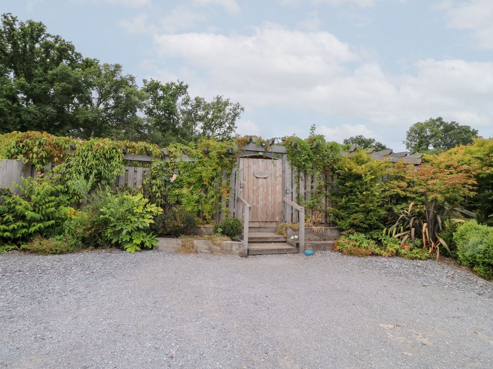 A garden with a wooden door and steps at Gloccamaura in Bovey Tracey