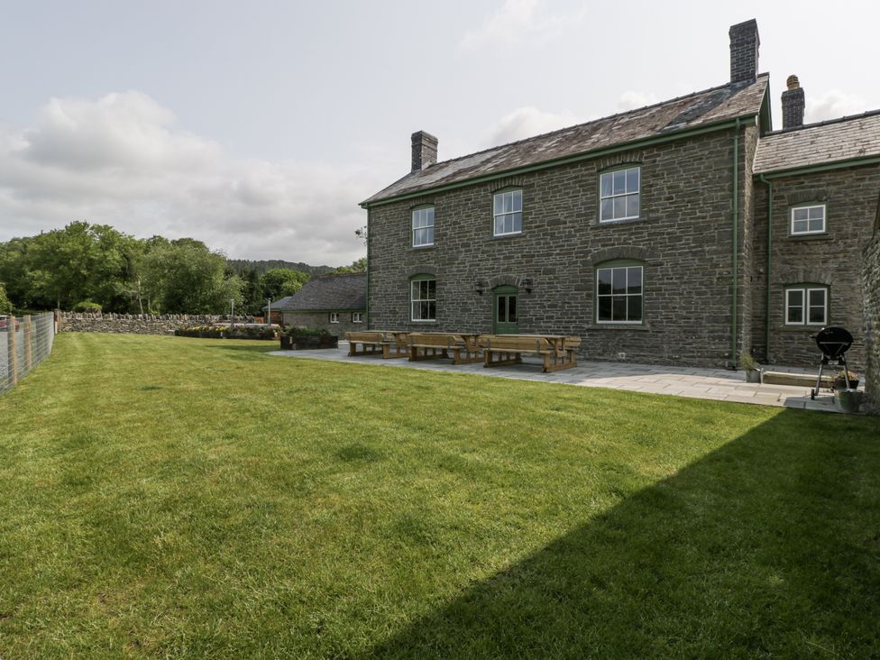 An outdoor area with a stone house, patio, table and chairs at Evenjobb Court Farmhouse near Presteigne