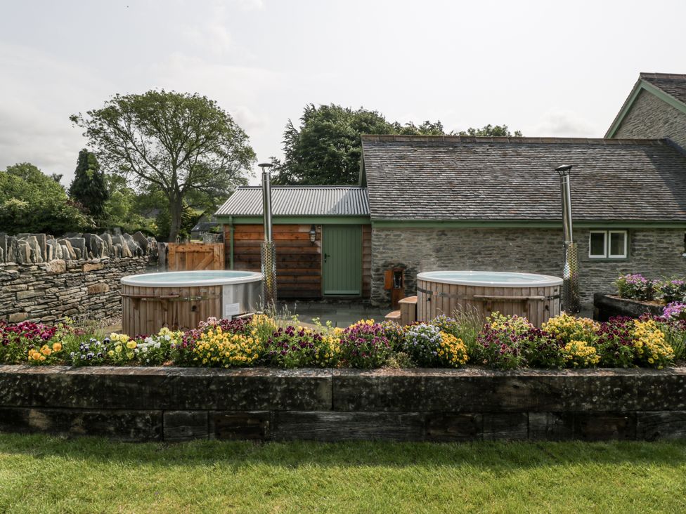 A garden with hot tubs and a flower bed at Evenjobb Court Farmhouse in Evenjobb near Presteigne
