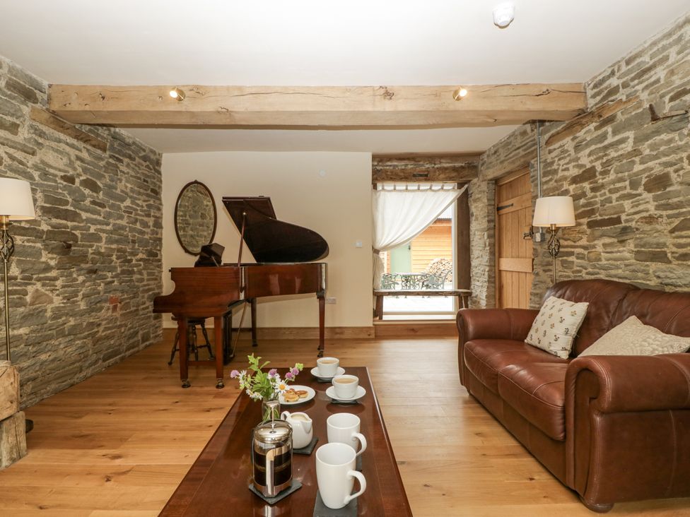 A living room with a grand piano and coffee table at Evenjobb Court Farmhouse near Presteigne