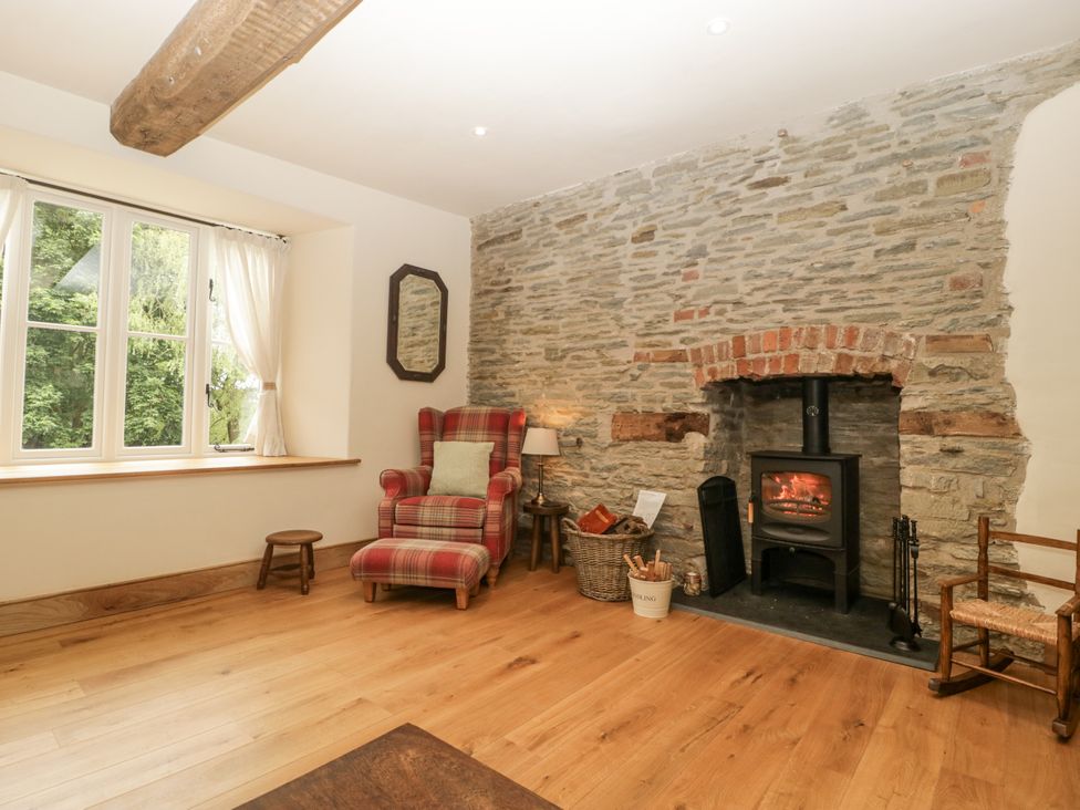 A living room with a fireplace and armchair at Evenjobb Court Farmhouse Evenjobb near Presteigne