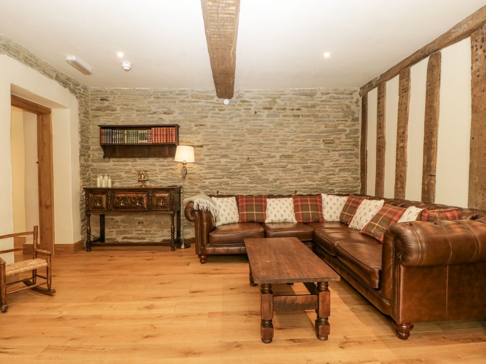 A living room with a leather sofa, coffee table, and bookshelf at Evenjobb Court Farmhouse near Presteigne