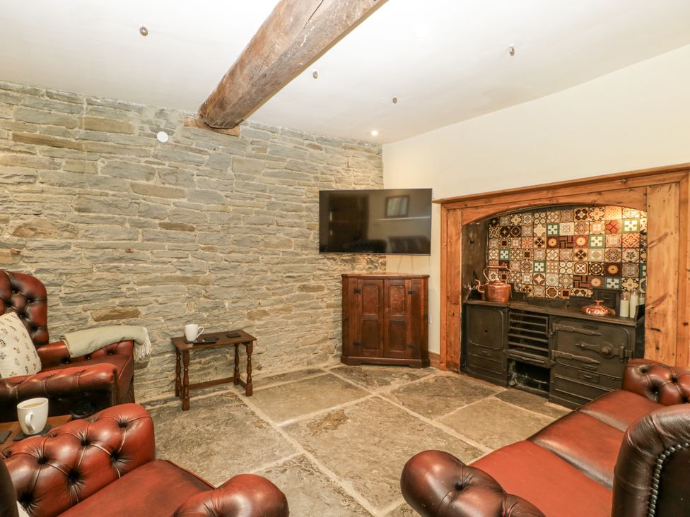 A snug room with leather chairs and a television at Evenjobb Court Farmhouse in Evenjobb near Presteigne