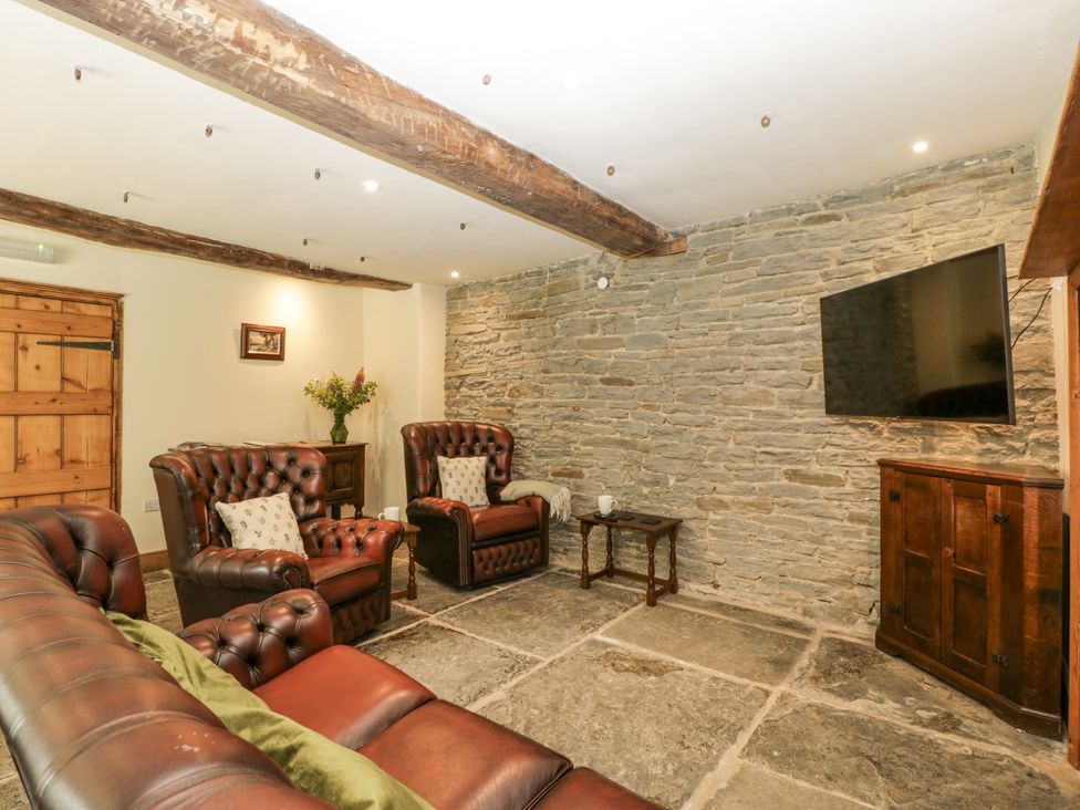 A snug with leather furniture and a TV at Evenjobb Court Farmhouse Evenjobb near Presteigne
